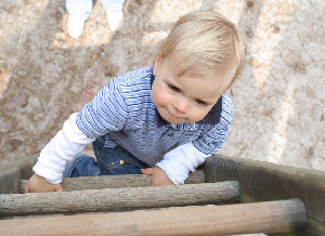 Ein Kind klettert auf ein Klettergerüst auf einem Sandkastenspielplatz.