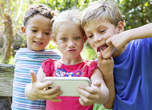 Drei Kinder fotografieren sich mit einem Smartphone
